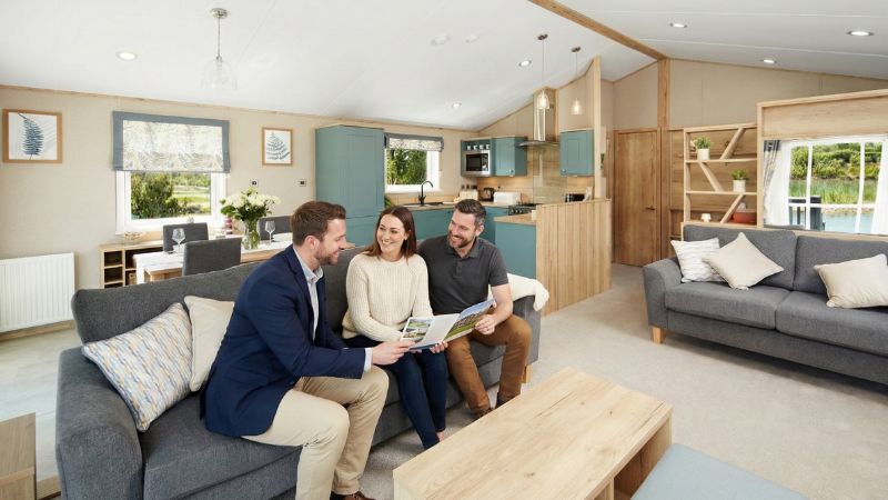 Couple discussing static caravan finance options with a park advisor inside a luxury holiday home