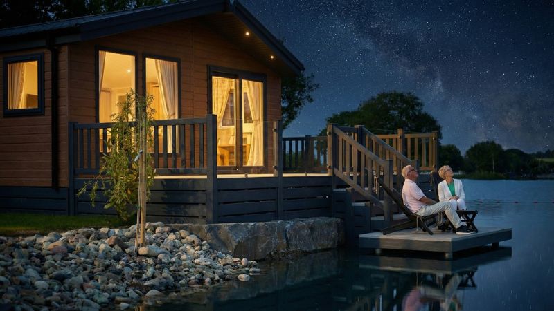 Couple stargazing from their holiday lodge decking at Green Meadow Holiday Park, Aberystwyth