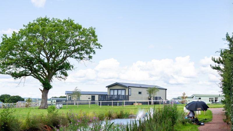 Static caravans and holiday lodges overlooking the fishing lake at Spring Lea Holiday Park, Shropshire