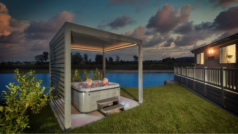 Couple relaxing in a hot tub at a holiday lodge at Green Meadow Holiday Park, illustrating the lifestyle available through finance