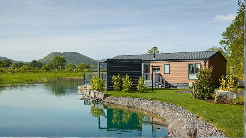 Static caravan holiday home with wraparound timber decking and outdoor furniture at a Mid Wales holiday park