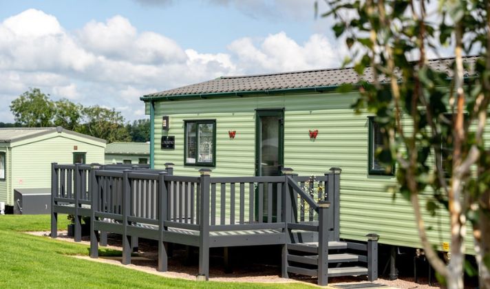 A well-maintained pre-owned static caravan with decking at a coastal holiday park