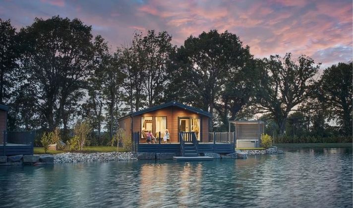 Couple relaxing with a drink on the decking of their holiday home in Mid Wales